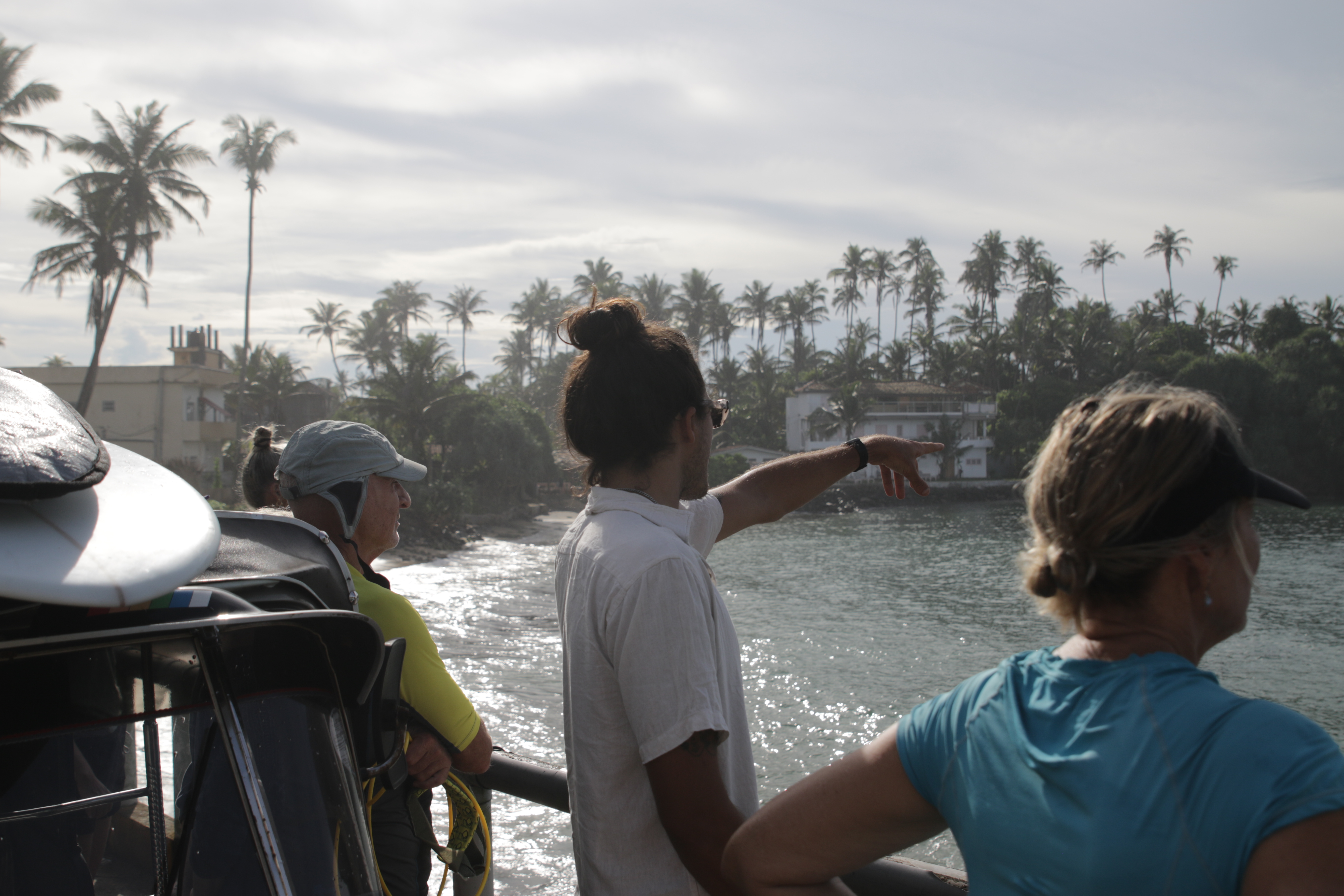 Guests and a coach beside surfboards and Lotus tuk-tuks at a Sri Lankan beach break
